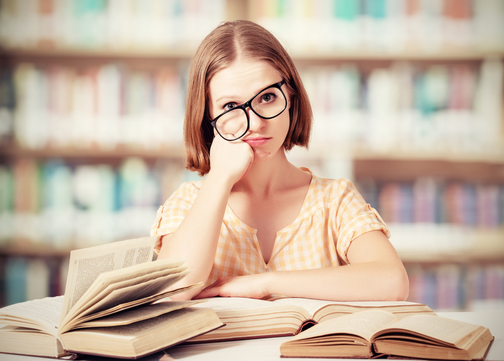 Студентка в очах читает в библиотеке обнаженной фото