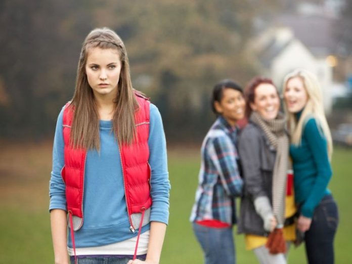 Upset Teenage Girl With Friends Gossiping In Background